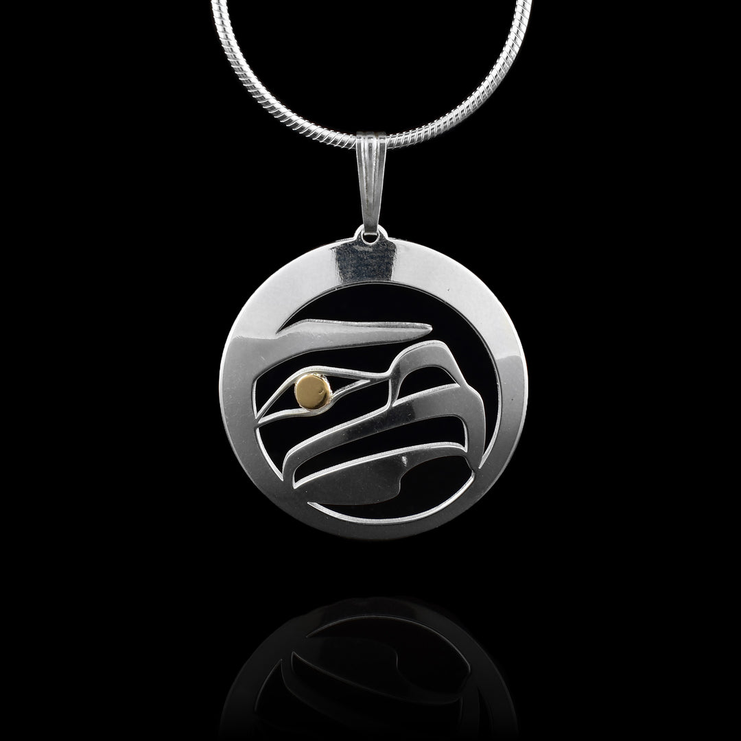This Eagle pendant has a circle ring made from sterling silver with a cutout depiction of the Eagle in the center of it. The cutout shows details of the head of the Eagle at a side profile with its nose, eye and beak. The eye is done using 14K gold.