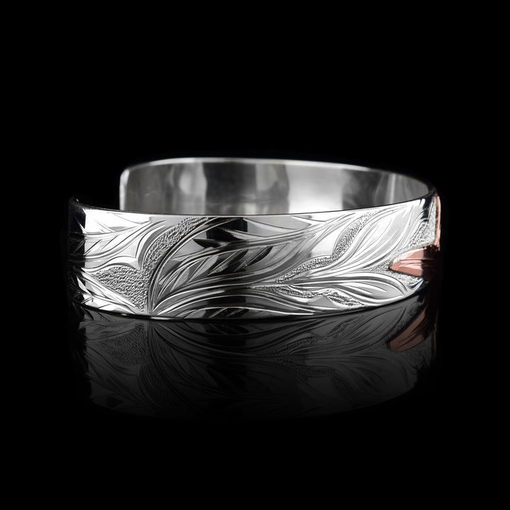 This sterling silver copper bracelet has a single band with a gap in the back. The head of the Hummingbird is done at a side profile using copper and there is a wing designs carved behind it on the band. On the other side there are floral design and its beak is reaching between two flower petals.