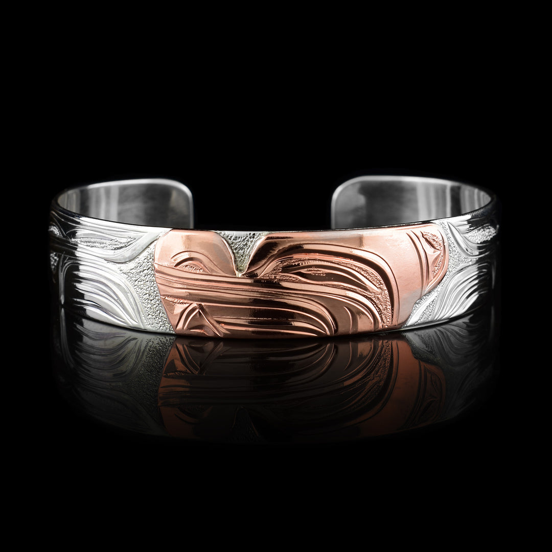This sterling silver copper bracelet has a single band with a gap in the back and the head of the Wolf is depicted in the center of it. The head is done in copper and at a side profile. On both sides of the band, there are carvings showing the body of the legend with its paws, claws and tail detailed in a side profile.