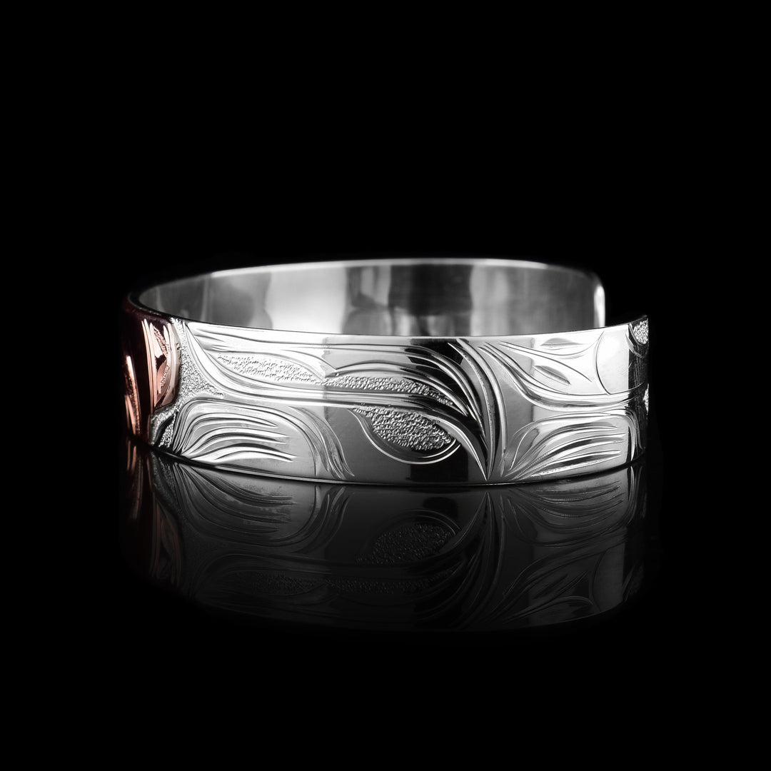 This sterling silver copper bracelet has a single band with a gap in the back and the head of the Wolf is depicted in the center of it. The head is done in copper and at a side profile. On both sides of the band, there are carvings showing the body of the legend with its paws, claws and tail detailed in a side profile.