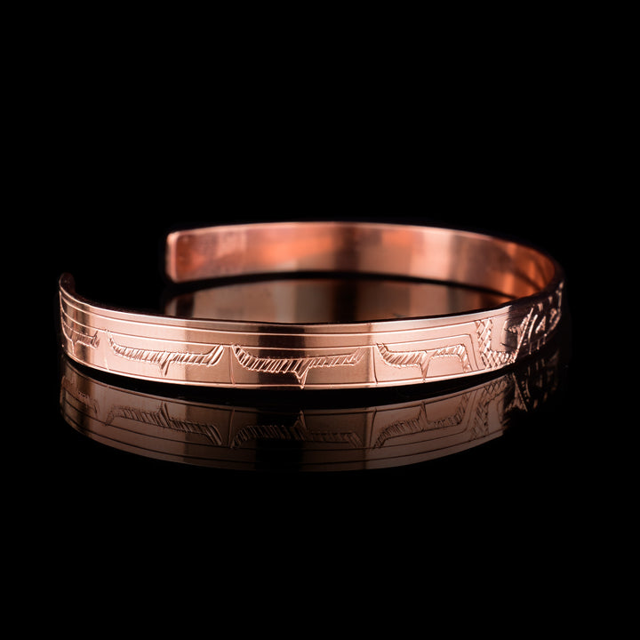 This Eagle bracelet has a single, thin band that is made form copper and has a gap in the back. The head of the Eagle is in the center of the band and is depicted at a side profile. The legend is depicted across the rest of the band.