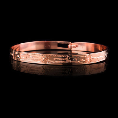 This Raven bracelet bangle has a thin, copper band with a clasp in the back. There are two Ravens carved at a side profile and their heads meet in the center of the band. There is a pearl that is held in their mouths and cross hatching designs in the background of the piece.