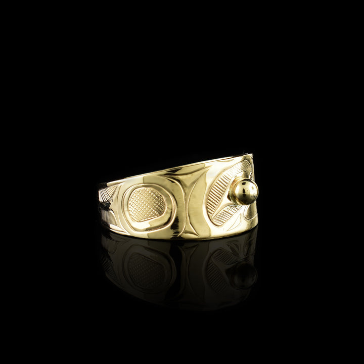 This Eagle gold ring has a wide band made from 14K gold and tapers in the back. The head of the eagle is beautifully carved at a side profile and its beak is open. There is a gold stud that is place in the eye and there are cross hatching designs in the background of the scene.
