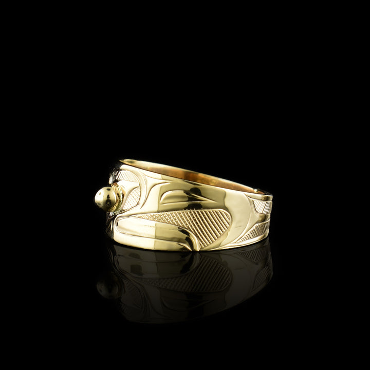 This Eagle gold ring has a wide band made from 14K gold and tapers in the back. The head of the eagle is beautifully carved at a side profile and its beak is open. There is a gold stud that is place in the eye and there are cross hatching designs in the background of the scene.
