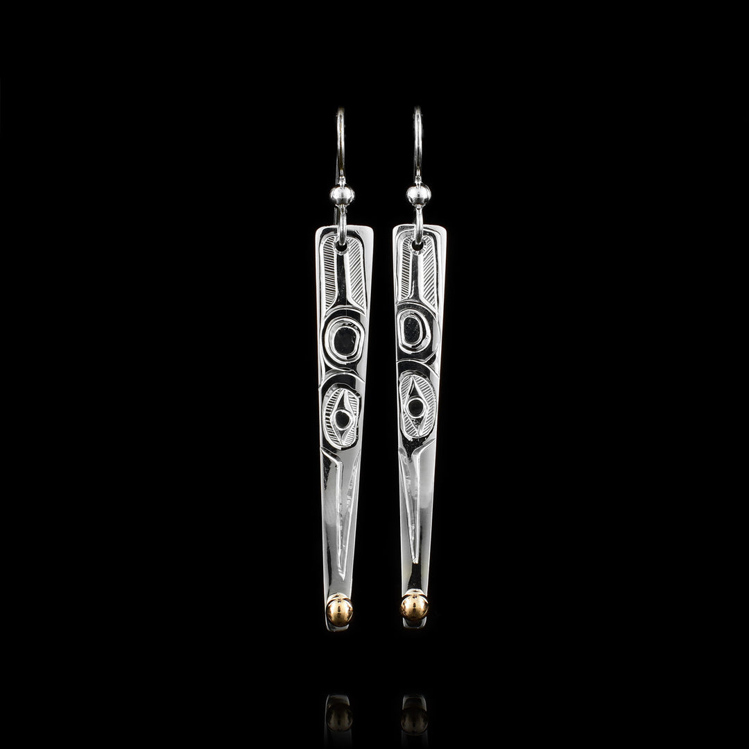 These long drop earrings have sterling silver have that are very long, thin upside down triangles. There are 14K gold studs at the very bottom of the hangs. The Hummingbird legend is carved at a side profile into the hangs. Its head is facing downward and there is a wing detail behind the head.