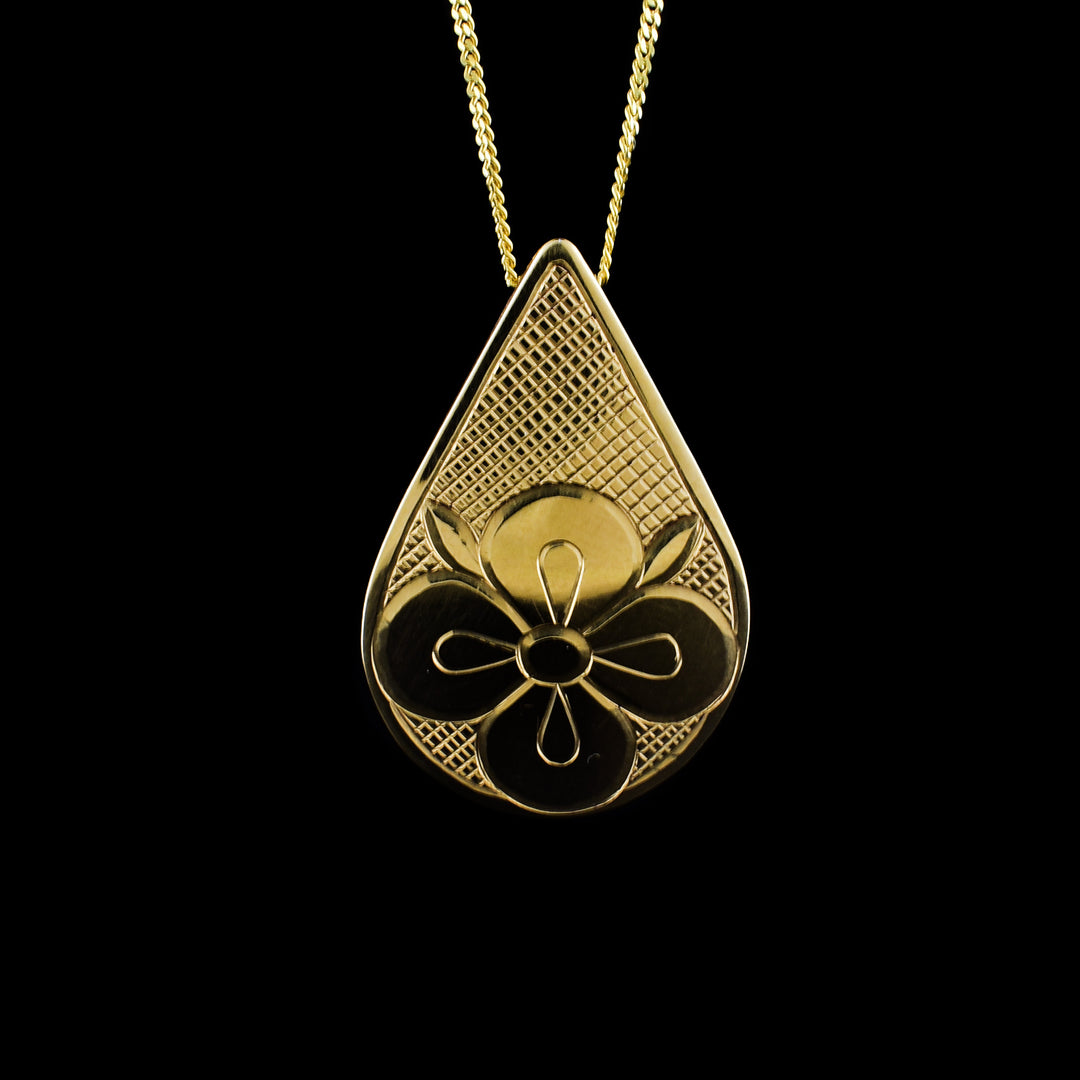 This 14K gold strawberry flower pendant is small and teardrop shaped. There is a flower carved at the bottom of the teardrop and cross hatching designs in the background.