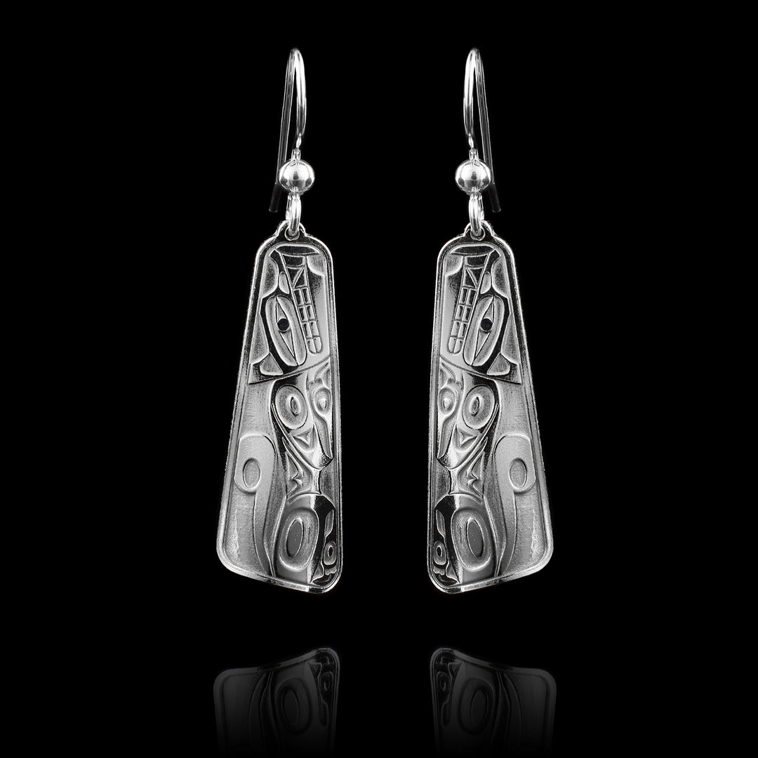 These dangle drop earrings silver have sterling silver hangs that taper out at the end and are rectangular. There is a full body depiction of the Wolf cast into the hangs at a side profile. The Wolf is crouched down with its head facing upward, its paws held underneath it and its tail curled up behind it.