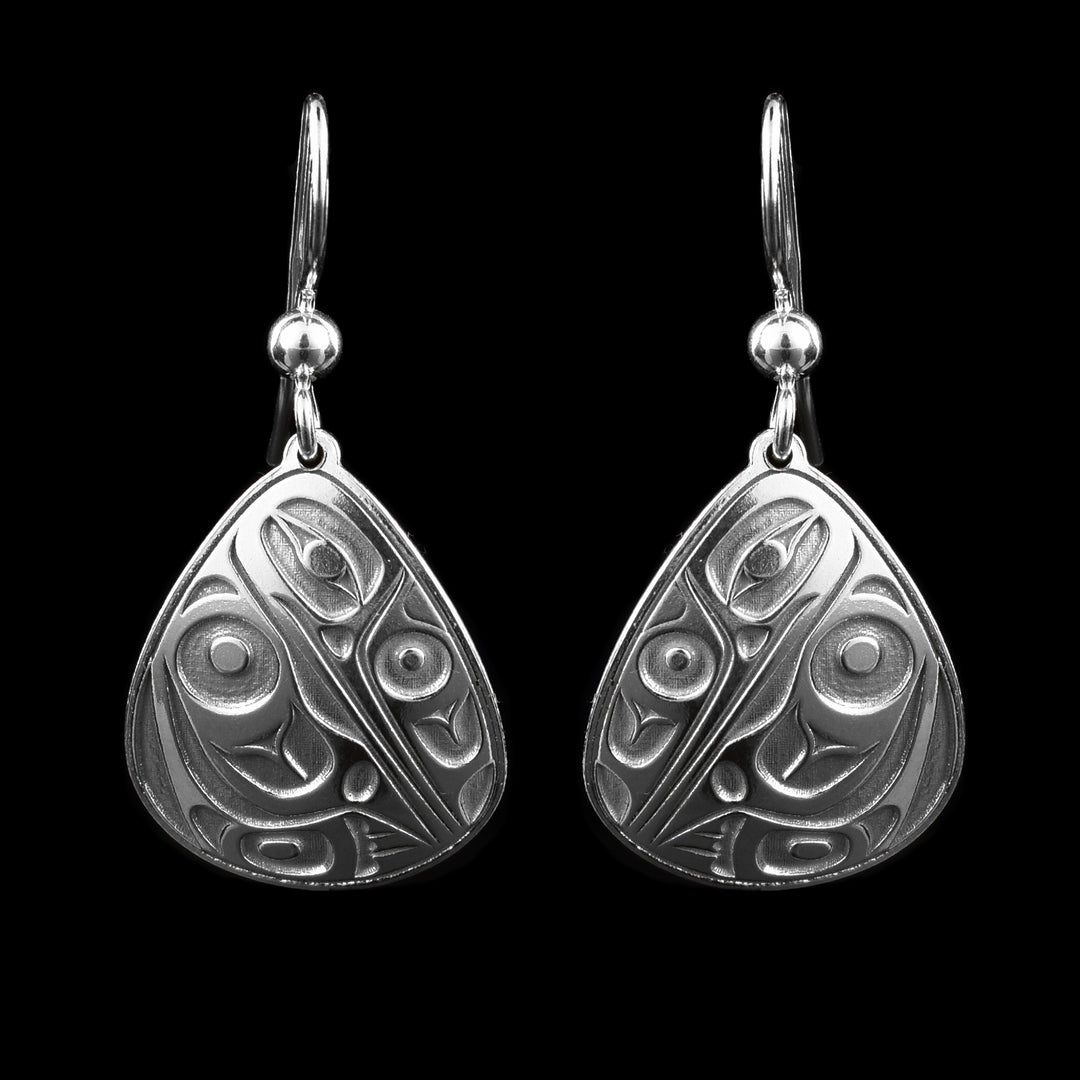 These Hummingbird dangle earrings have triangle shaped hangs that re very rounded on their edges. The hangs are sterling silver and there is a side profile depiction of the Hummingbird casted into them. The head is looking down with ne large eye in it and its wing and tail rest underneath the head.