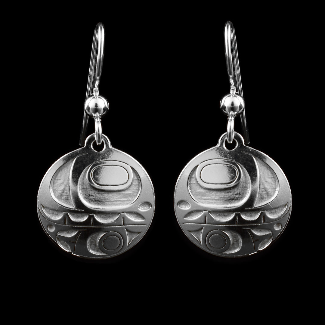 These small dangle earrings have circle shaped hangs made from sterling silver.  There are abstract designs representing the Orca cast into the hangs. There is a large eye with teeth below it and a fin design at the bottom.
