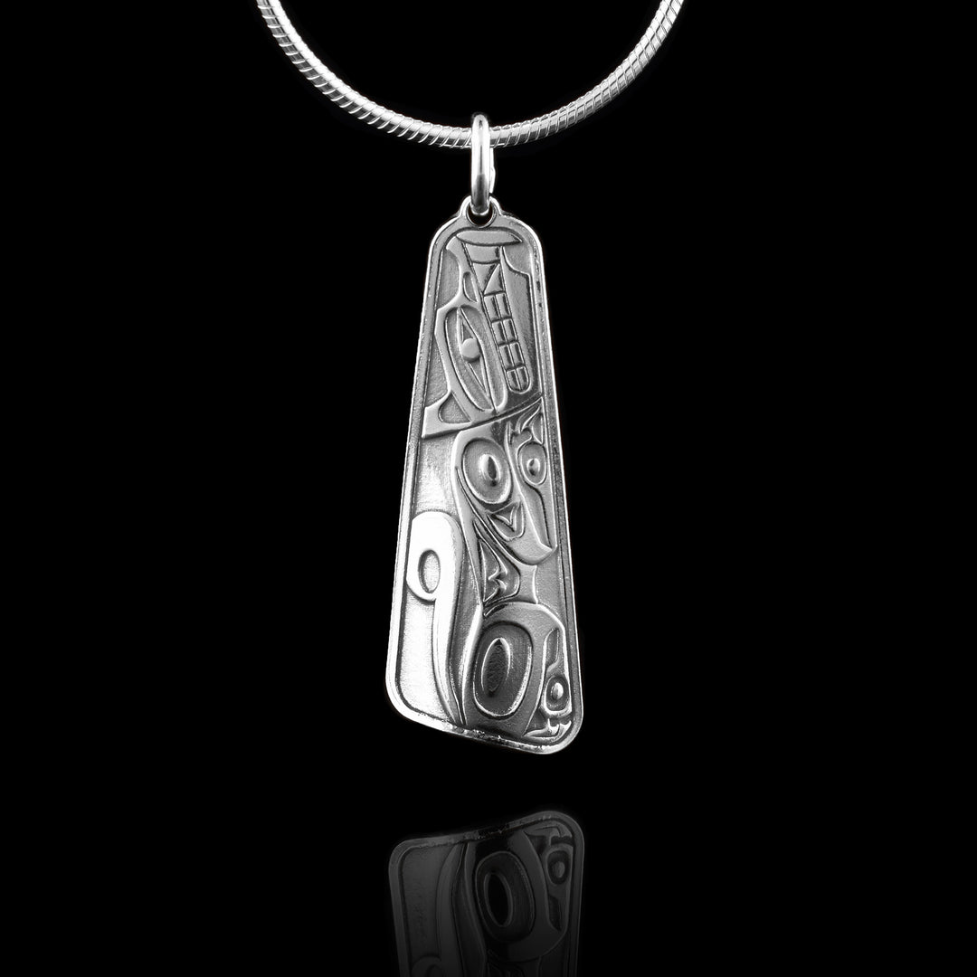 This sterling silver Wolf pendant is long and tapers in at the top of the piece. A full body of the Wolf legend is cast into the pendant at a side profile. Its head is at the top with its arms and paws tucked in and tail curled up behind it. Its eye, teeth. ears and claws are detailed.