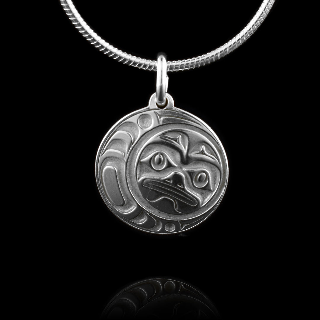 This Moon silver pendant has a circle shape and is made from sterling silver. There are depictions of the full moon cast into the pendant with eyes, eyebrows, nose and mouth. There are crescent designs on the side of the hangs around the legend.