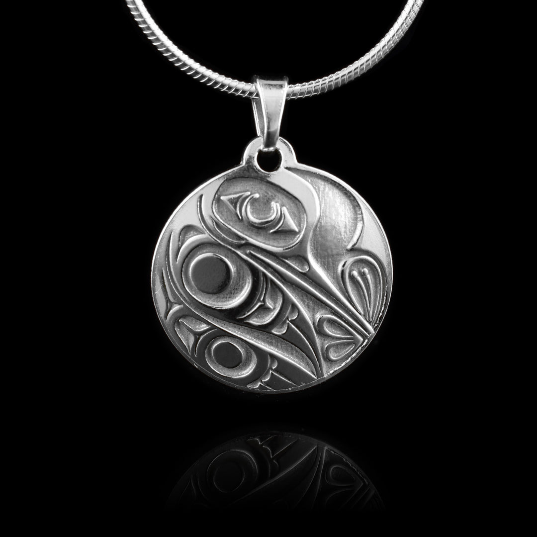 This Hummingbird silver pendant has a circle shape made from sterling silver. There is a depiction of the Hummingbird cast into the pendant at a side profile. The top half consists of the eye, beak and nose and below is a wing design with feather details included.