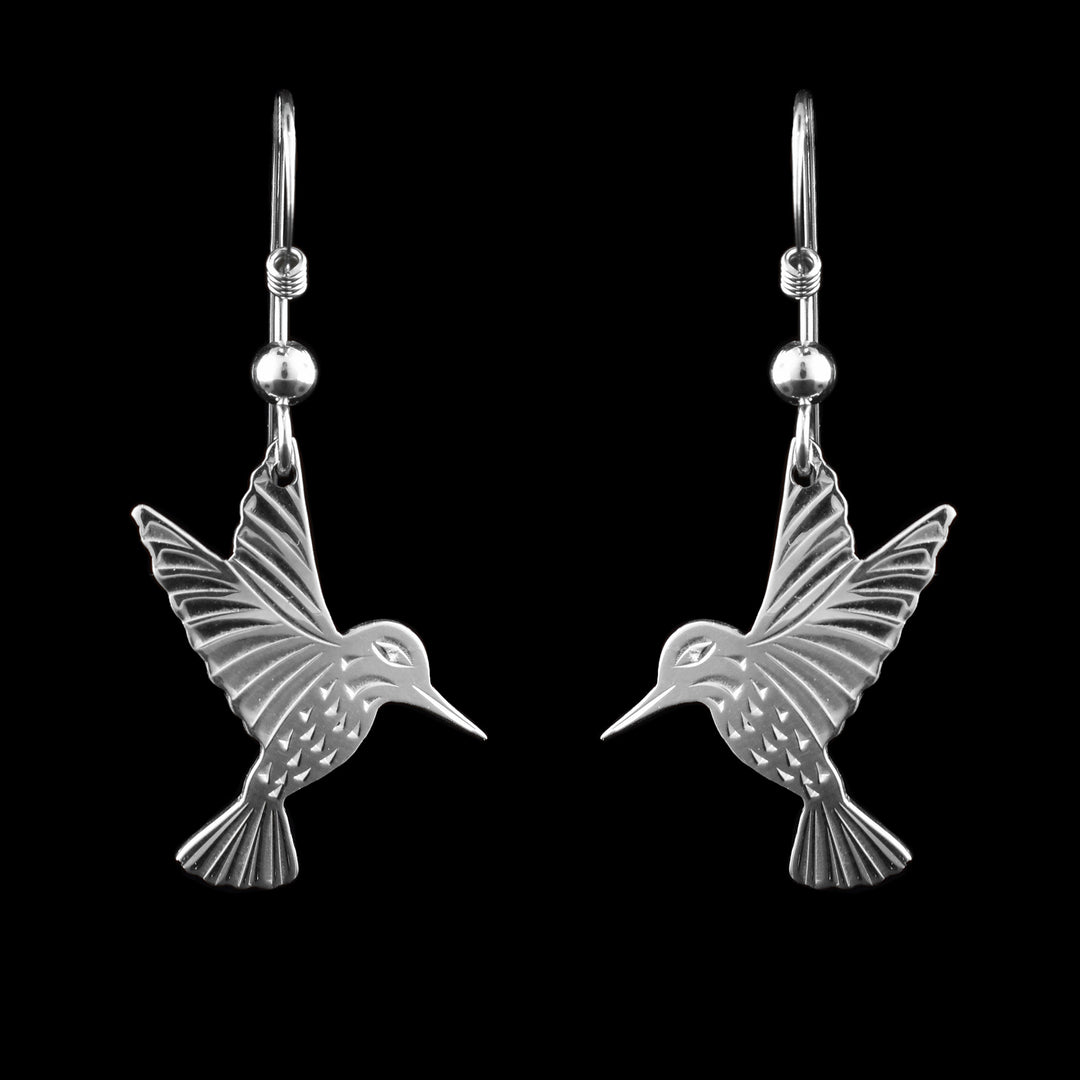 These Hummingbird earrings silver have cutout hangs made from sterling silver that are shaped like a Hummingbird. Its beak is pointed downwards and its wings are extended upwards above its head. There are beak and eye detailed carved as well as designs on its throat. There are feather patterns across the body, tail and wings.
