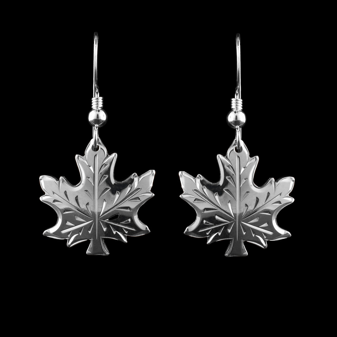 These maple leaf earrings are made from sterling silver and have the shape of a Canadian maple leaf. There are carvings on the leaf showing the designs.