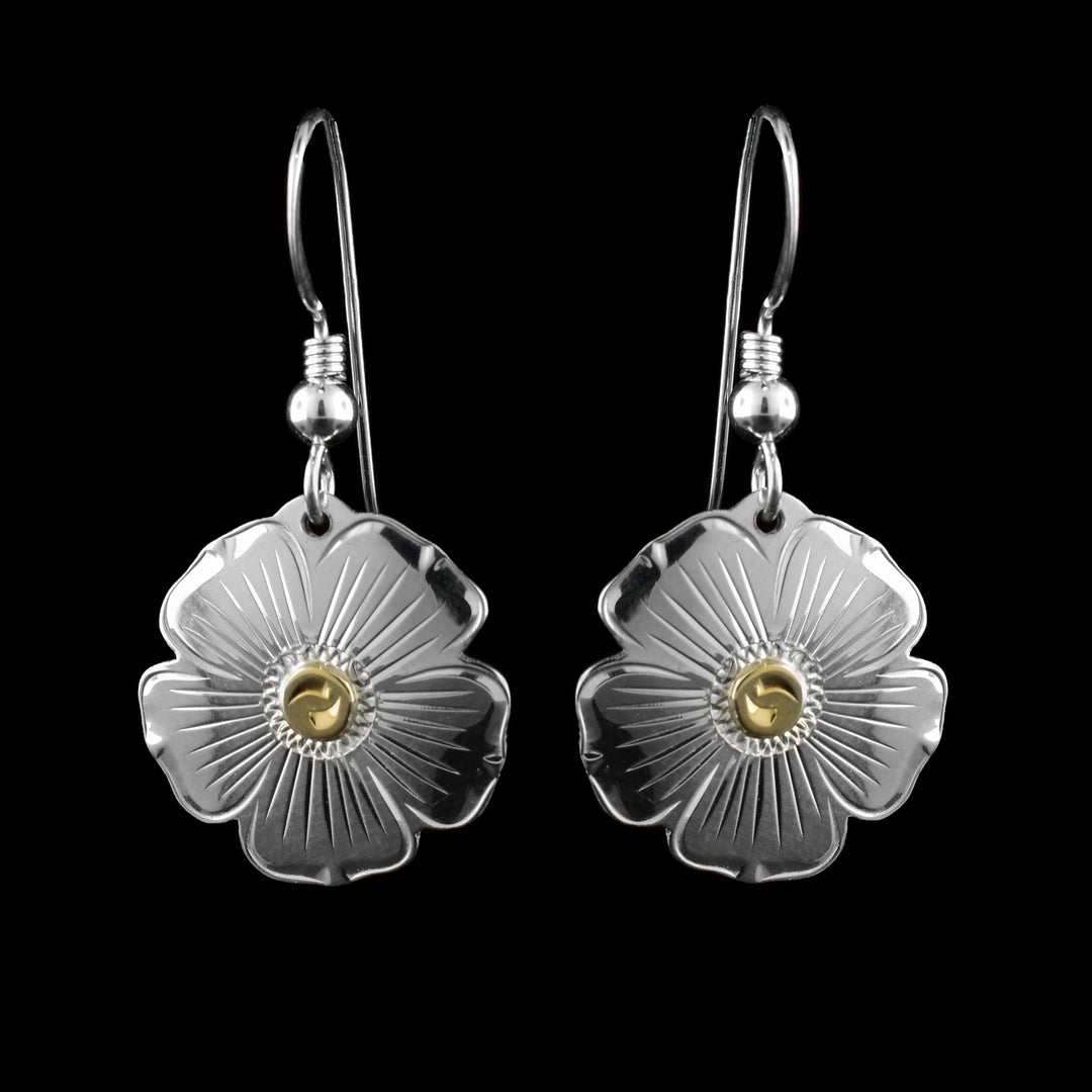 These sterling silver flower earrings have dangling hangs that have been cutout to depict flowers. There are five, wide petals with carvings on the surface of them detailing the flower. There is 10K gold circles in the center of the flower.