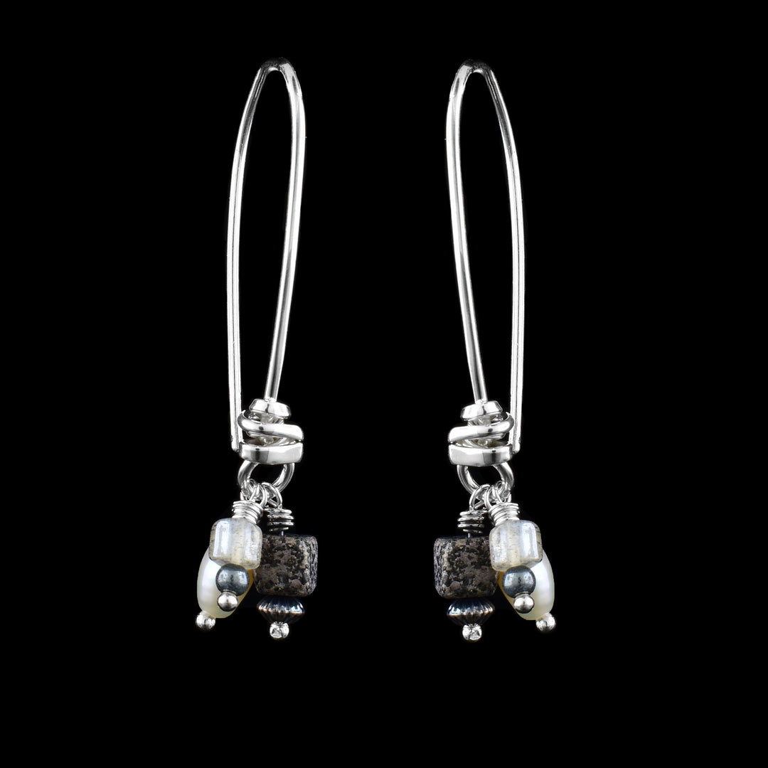 These charm earrings have long, sterling silver hoop hooks with clusters of ems at the bottom. There are pearl, pyrite cube and labradorite charms dangling at the bottom of the hoop hooks.