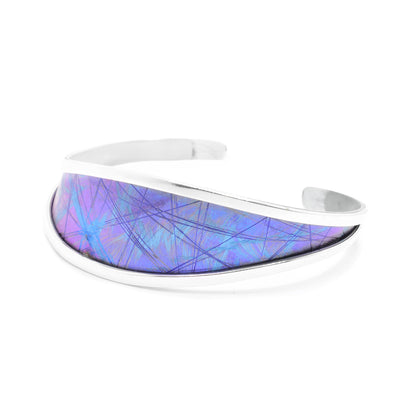 This titanium bangle bracelet has a wider top with a titanium piece held between sterling silver bands. The piece tapers towards the back into just the silver bands and there is a gap. There are blue and purple designs made in the titanium by anodizing the material