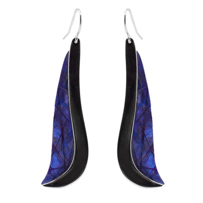 These titanium drop earrings have long, wavy hangs that are wider at the bottom than the top. One end is line with a sterling silver band that follows the edge of the hangs and the other side is made from anodized titanium. The titanium has a blue color with purple design on its surface.