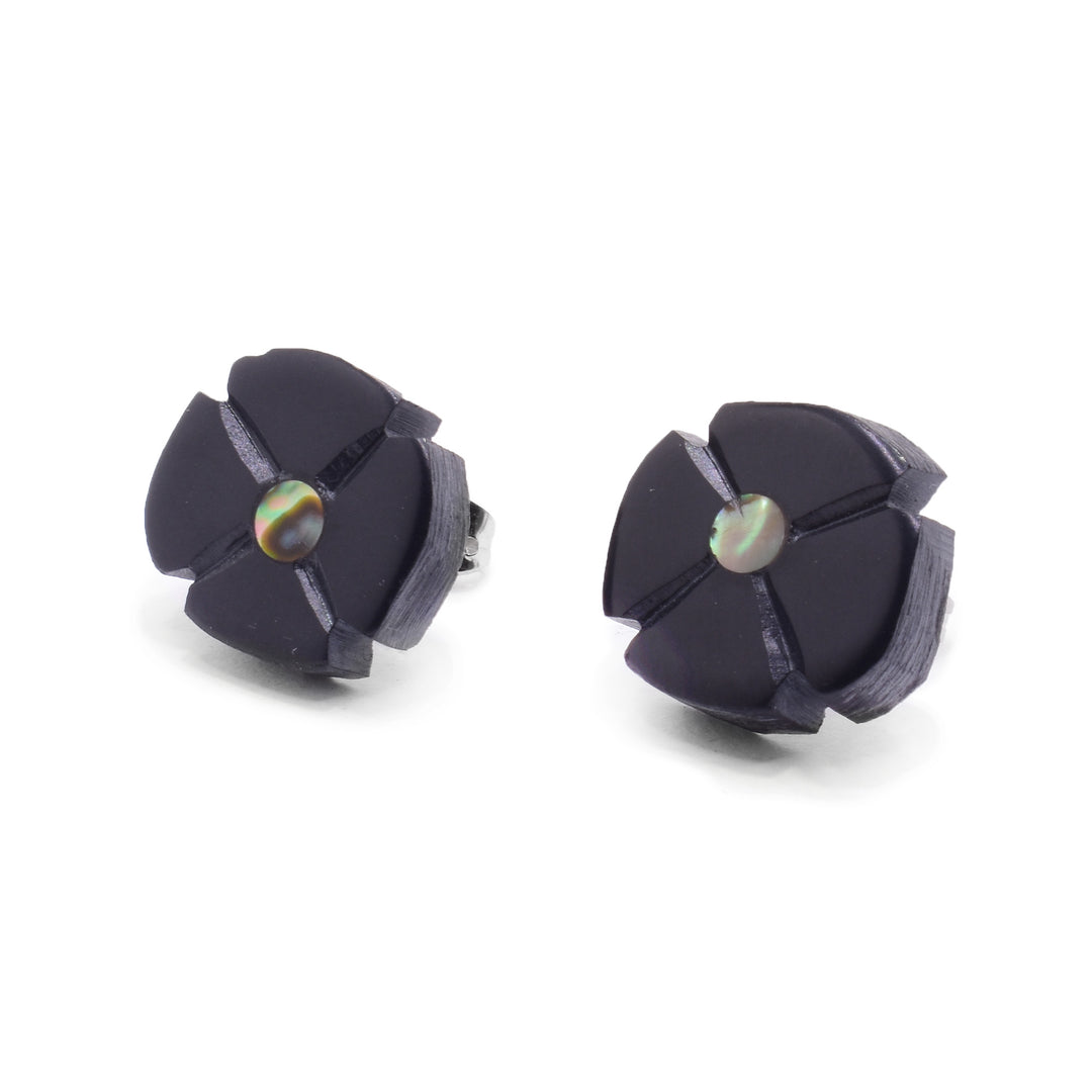 These abalone stud earrings are carved from argillite stone to depict a flower. There are four petals carved into the circle shaped studs and an abalone piece set in the center of them.