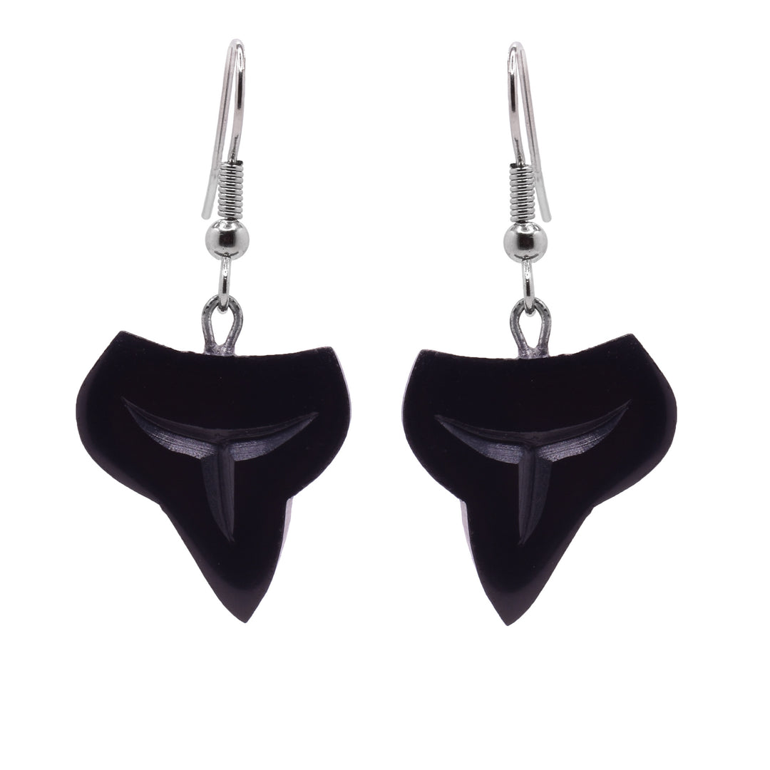These dangling shark tooth earrings have hangs that have been carved from argillite stone. The hangs have wide, crescent shapes with the ends pointing up and below it drops down into a sharp point. There are simple line designs carved into the hangs detailing the shark tooth.