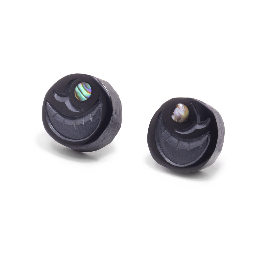 These argillite stud earrings are circle shaped and carved from argillite stone to depict the egg of the Salmon. There are designs carved into the stud including a crescent shape and a round piece of abalone depicting the embryo.