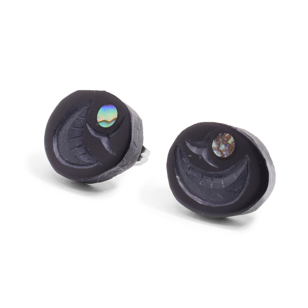 These argillite stud earrings are oval shaped and carved from argillite stone to depict the egg of the Salmon. There are designs carved into the stud including a crescent shape and a round piece of abalone depicting the embryo.