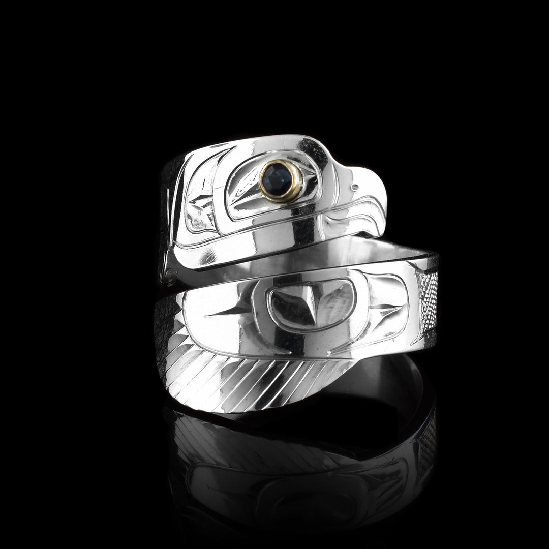 This Eagle ring has a sterling silver wide band that wraps around the finger twice. The top band  is carved to depict the head of the Eagle and the bottom one depicts its wing. There is a sapphire gem that is embedded into the eye of the legend.