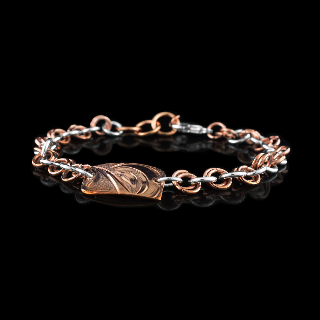 This sterling silver copper chain bracelet has double copper links hooped through double silver links to make the chain. There is a rectangle shaped plate made from copper with a side profile of the Hummingbird head carved into it.
