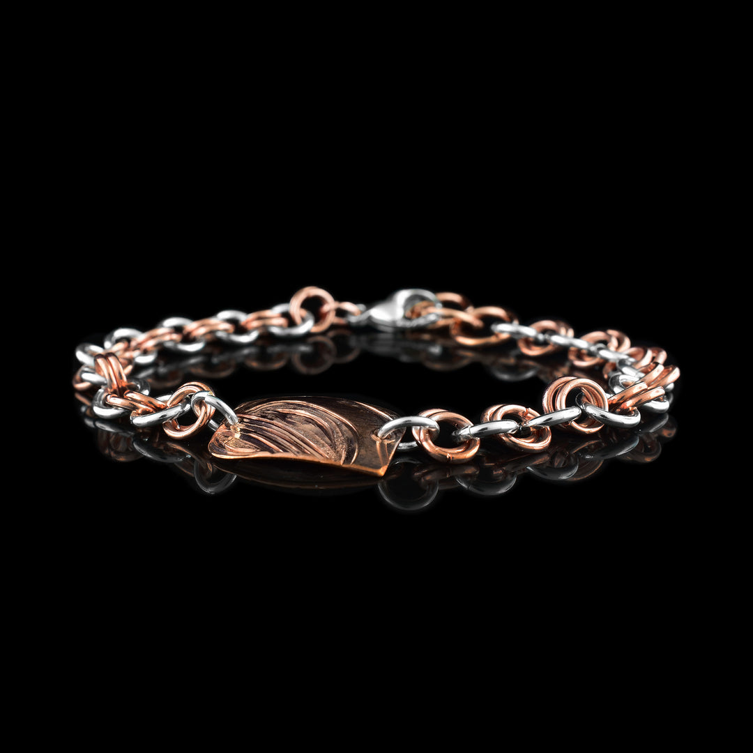 This sterling silver copper chain bracelet has double copper links hooped through double silver links to make the chain. There is a rectangle shaped plate made from copper with a side profile of the Orca head carved into it.