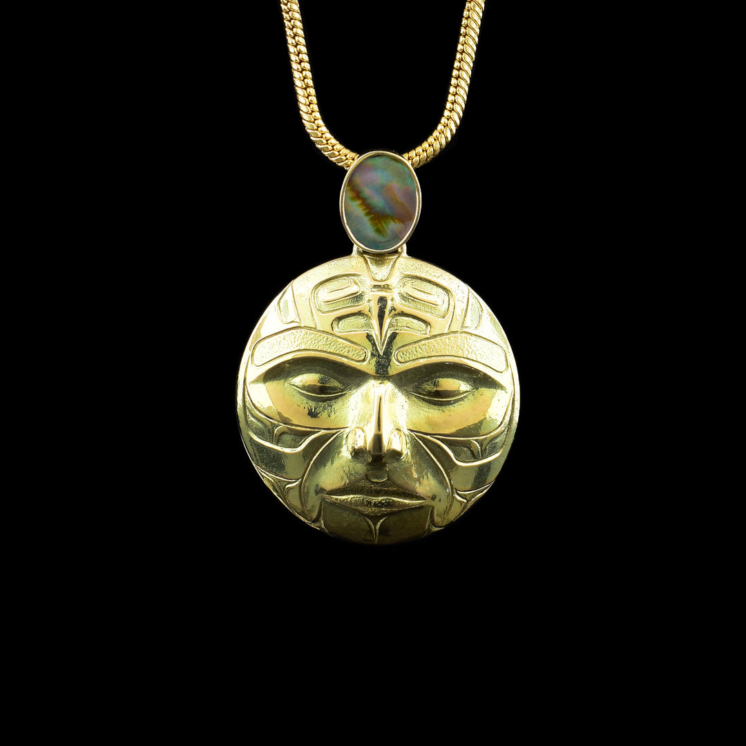 14K Gold Abalone Moon Pendant, the moon legend is carved into the circular piece of 14k gold. A abalone shell sits above the moon.