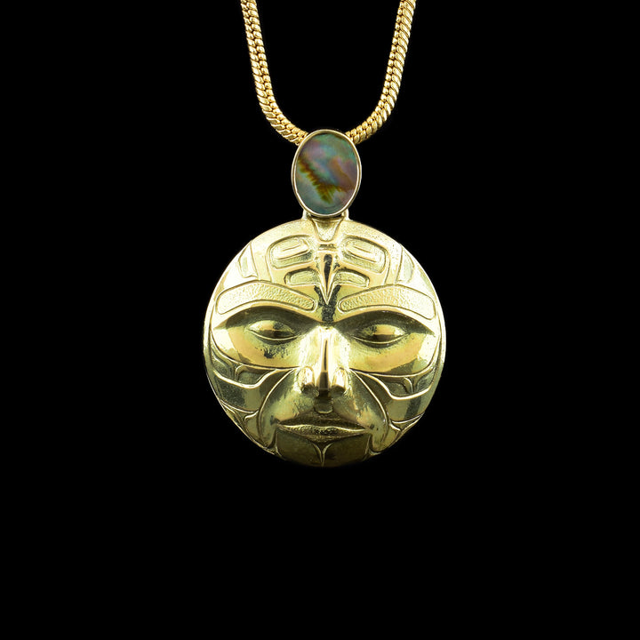 14K Gold Abalone Moon Pendant, the moon legend is carved into the circular piece of 14k gold. A abalone shell sits above the moon.