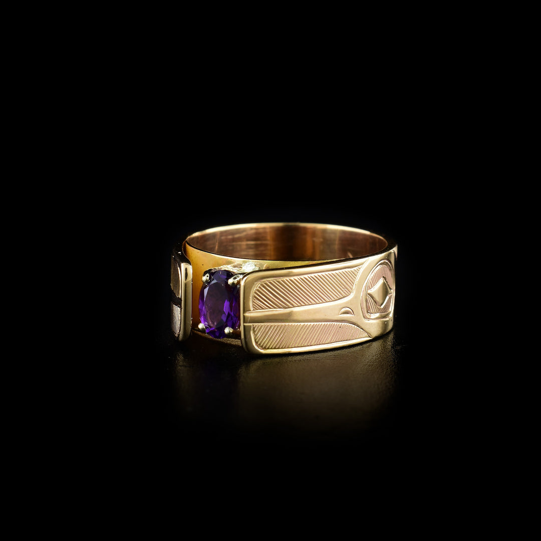 This Hummingbird solitaire ring has a 14K gold band with carvings of the side profile of the Hummingbird head made on either side of the gem. The beaks of the Hummingbird are facing the amethyst gem. The band extends above the gem and frames it in a cathedral style.