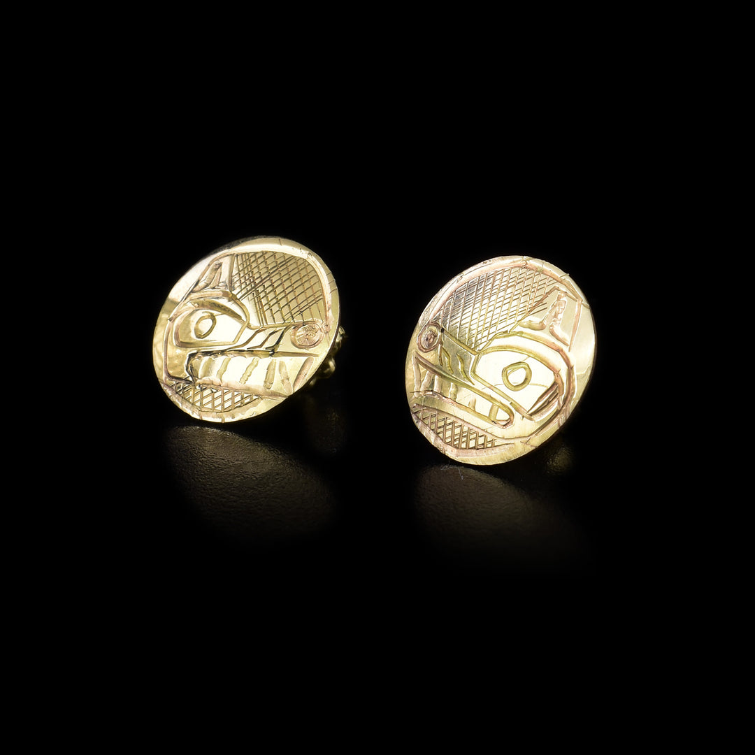 Circular 14K yellow gold stud earrings featuring wolf heads with cross-hatching background. Each wolf has a long snout with teeth showing and a perky ear.