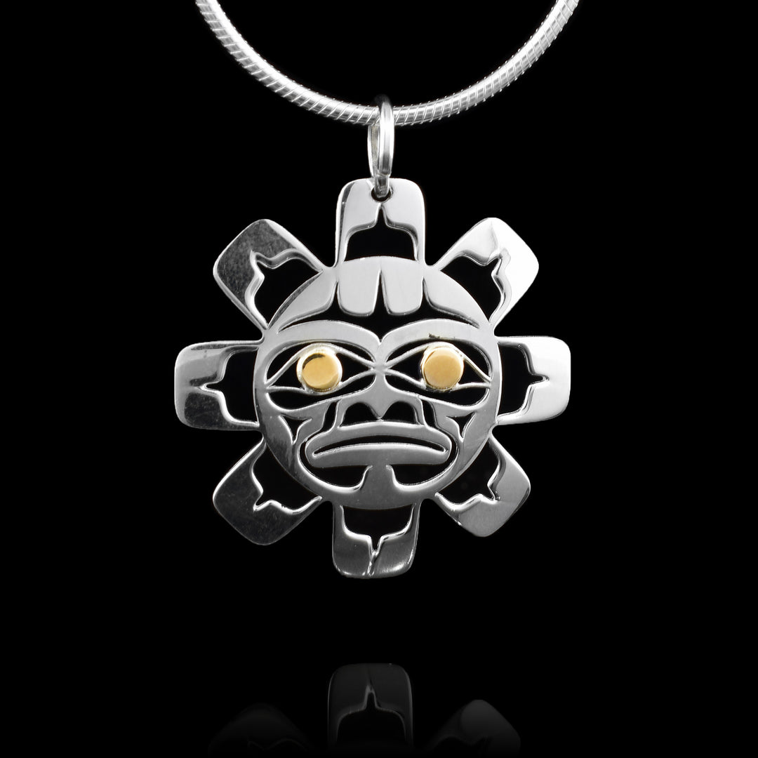 This sun pendant is handcrafted. It features an elegant sun design cut out from a polished sterling silver circular frame with eight rays around the face. With a solid surface and cut-out lines to create the sun's face. The sun is shown front-facing with eyes that are 14k gold.