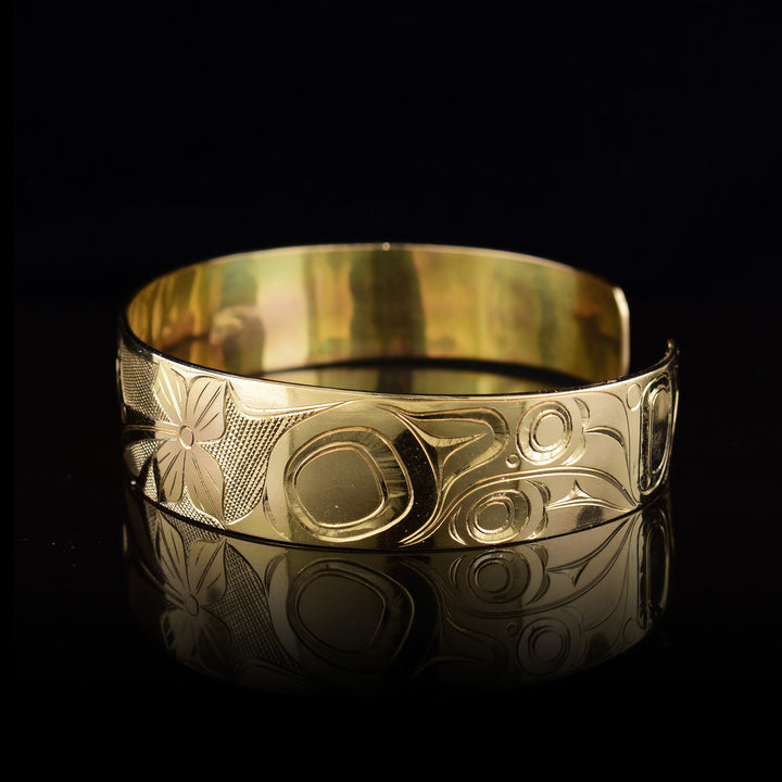 Left side of the gold cuff bracelet depicts intricate carvings representing the wings and feathers of the Hummingbird.