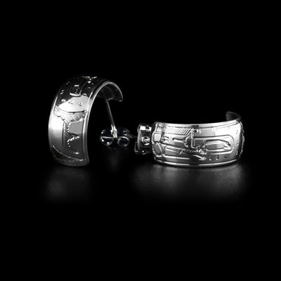 These wide hoop earrings are made from sterling silver and have wide bands curved into half hoop stud earrings. The head of the Raven is carved into the bands with its beak facing the studs and there is a wing detail behind the head.