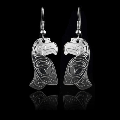 These sterling silver dangling earrings have hangs that are shaped like the Eagle legend. The Eagle is depicted in the side profile with its head at the top and one wing tilted in front of it and its tail curves out behind it. There are carvings made on the surface of the hangs also depicting the details of the Eagle legend.