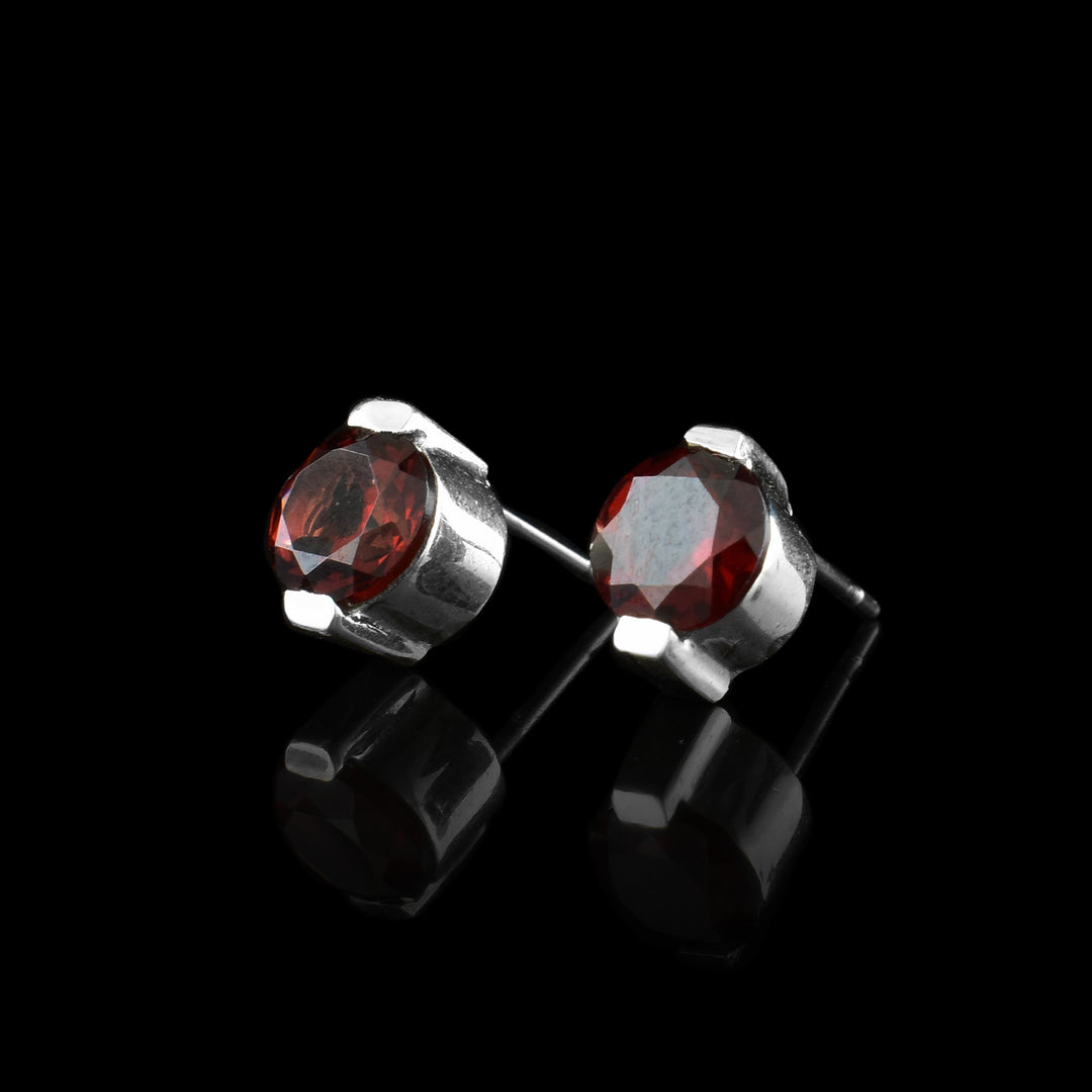 These garnet stud earrings have red garnet gems held in sterling silver. The studs have two claws holding the top and the bottom.