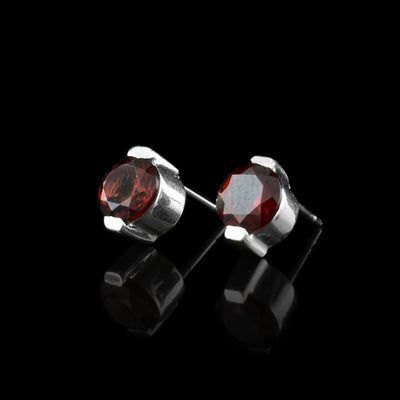 These garnet stud earrings have red garnet gems held in sterling silver. The studs have two claws holding the top and the bottom.