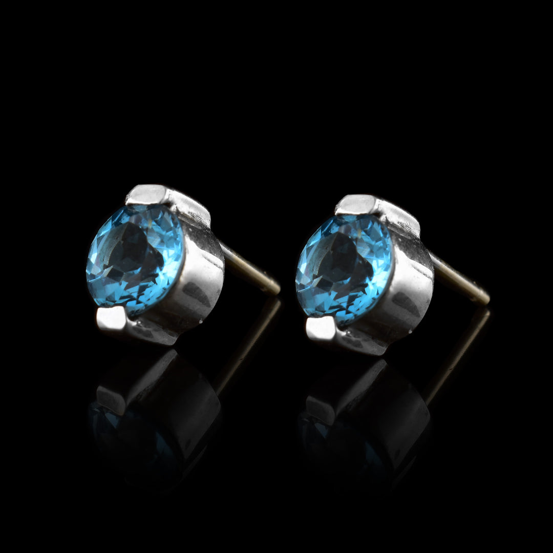 These blue topaz stud earrings have topaz gems held in sterling silver. The studs have two claws holding the top and the bottom.