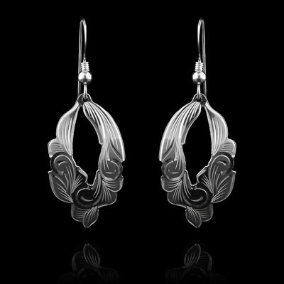 These floral dangle earrings are made from sterling silver and have roughly oval shaped hangs. There is a cutout in the center of the hangs making them appear like hoops and the edges of them follow that shapes of the floral designs. Thee are carvings on the hangs resembling leaves and petals.