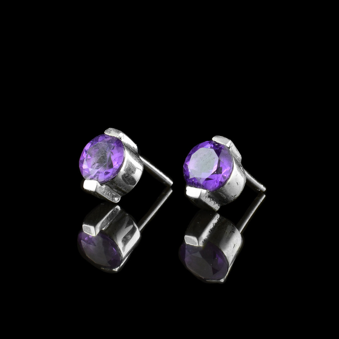 These amethyst stud earrings have purple amethyst gems held in sterling silver. The studs have two claws holding tat the top and the bottom.