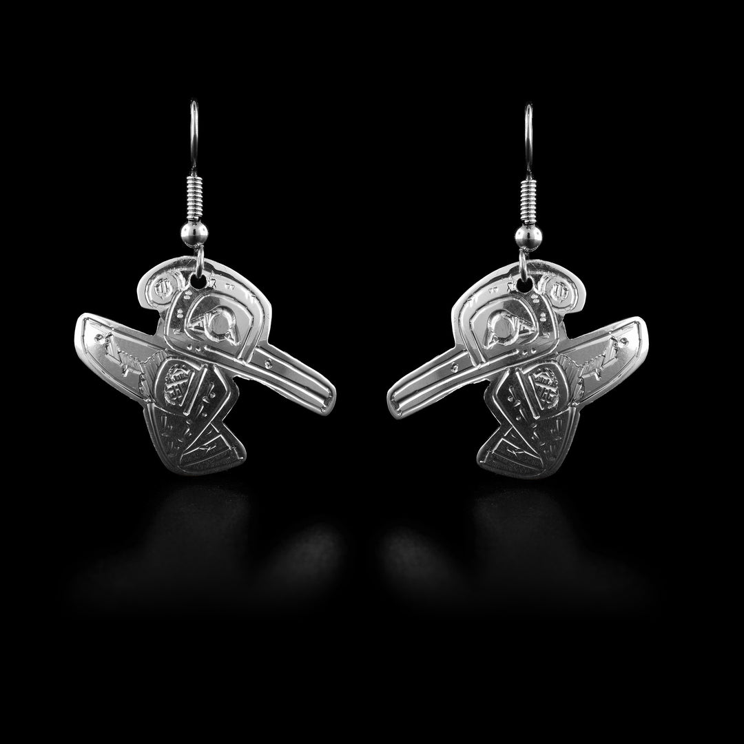 These Hummingbird dangle earrings have Hummingbird shaped hangs and are made from sterling silver. The Hummingbird is also carved into the hangs at a side profile. its head is looking down and its beak extends out, on the other side, there is a small feather detail on its head and its wing etends out the other side.