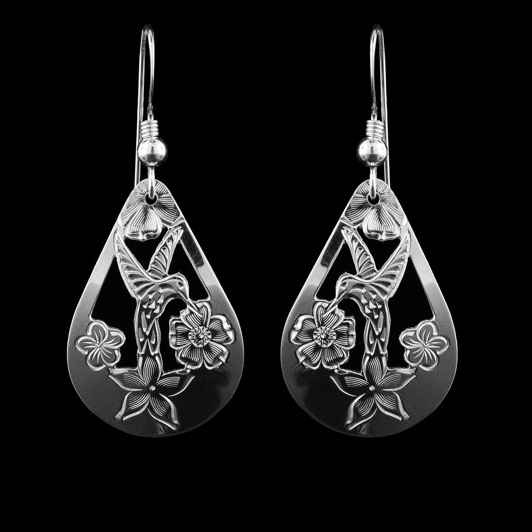These dangling Hummingbird earrings are made from sterling silver and have teardrop shaped hangs. There are cutout designs and carvings on the surface of the hangs depicting a hummingbird among flowers.