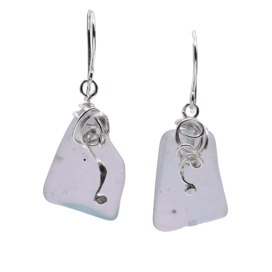 These dangling sea glass earrings have rough, rectangle shaped sea glass hangs. The glass is clear and foggy with sterling silver charms hanging from the hooks that represent sea kelp.