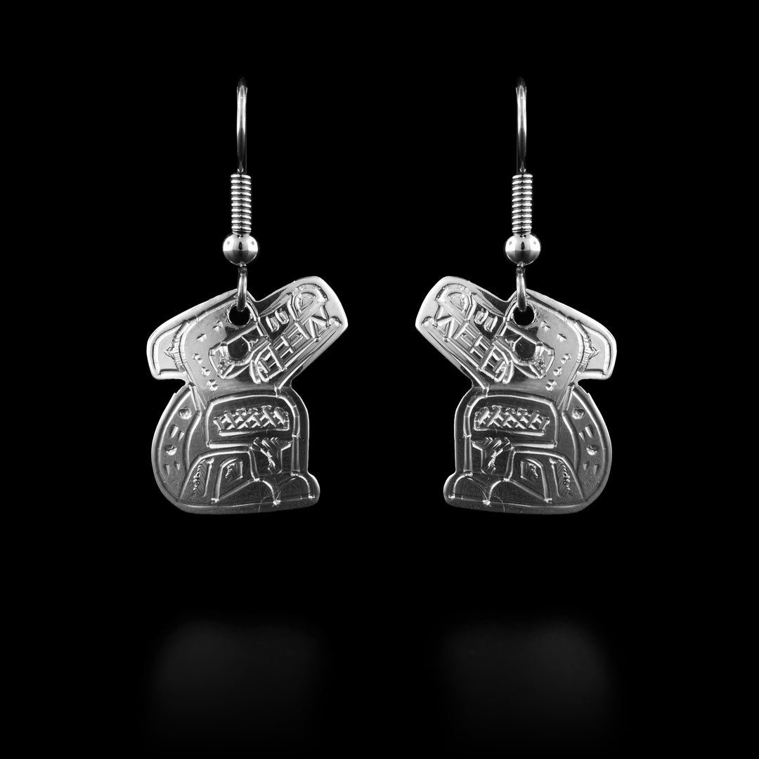 These Wolf dangle earrings have Wolf shaped hangs and are made from sterling silver. The Wolf legend is also carved into the hangs with its head looking upwards, all feet on the ground and its tail curled up behind it. Its teeth are bared.