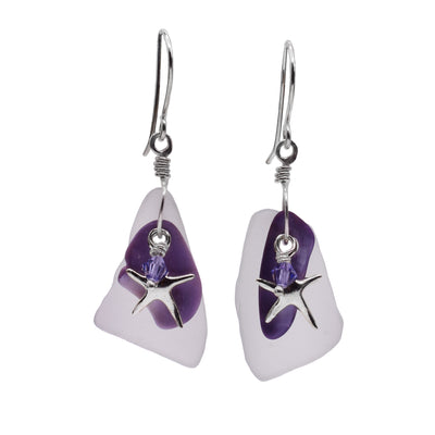 These ocean earrings have rough shaped, sea glass hangs that are somewhat clear and foggy. There are charms dangling from the hooks including a purple sea shell, a steering silver starfish and amethyst Swarovski crystals.