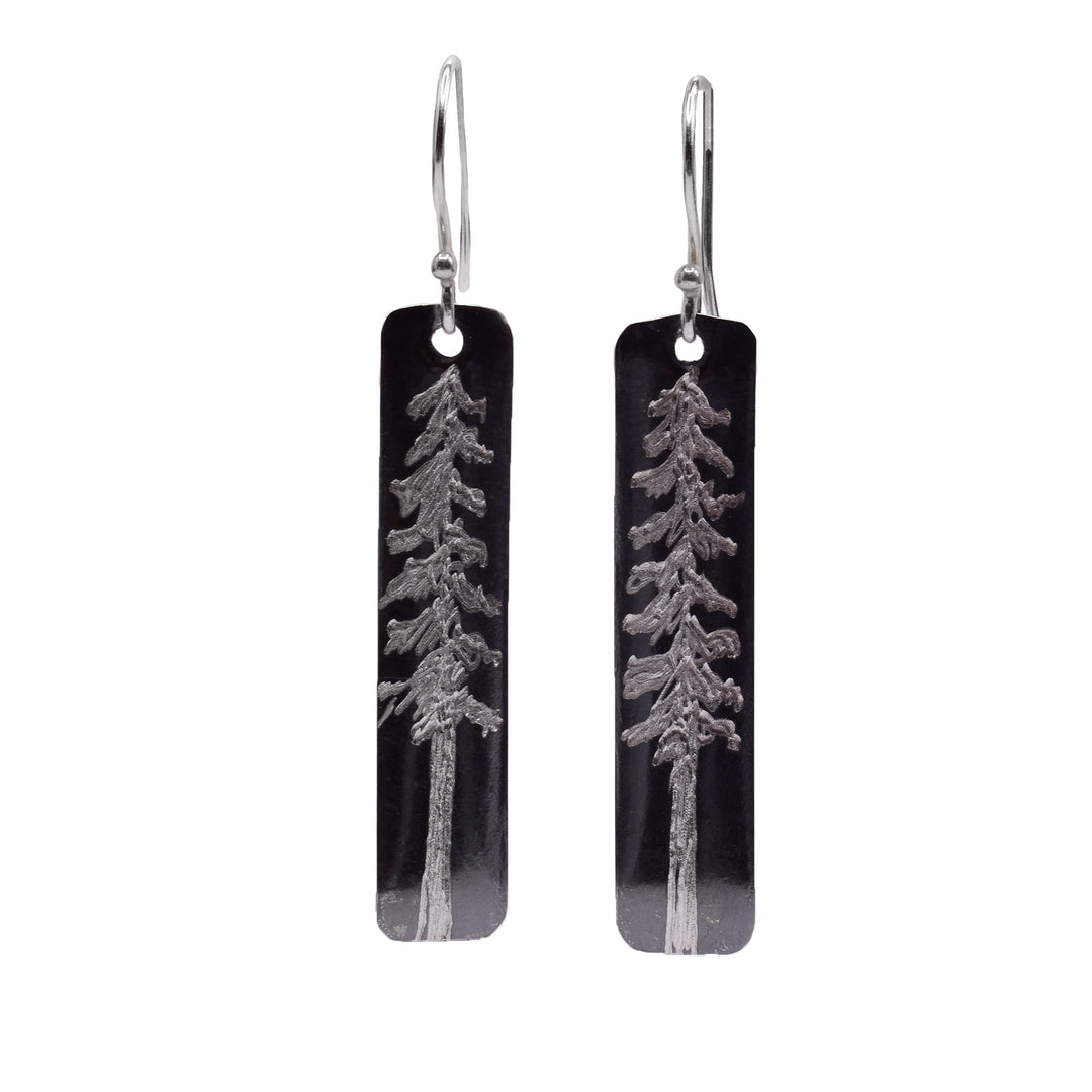 These tree earrings have long, thin and rectangle shaped hangs that are made from sterling silver. There are depictions of tall pine trees that are carved into the surface of there hangs.