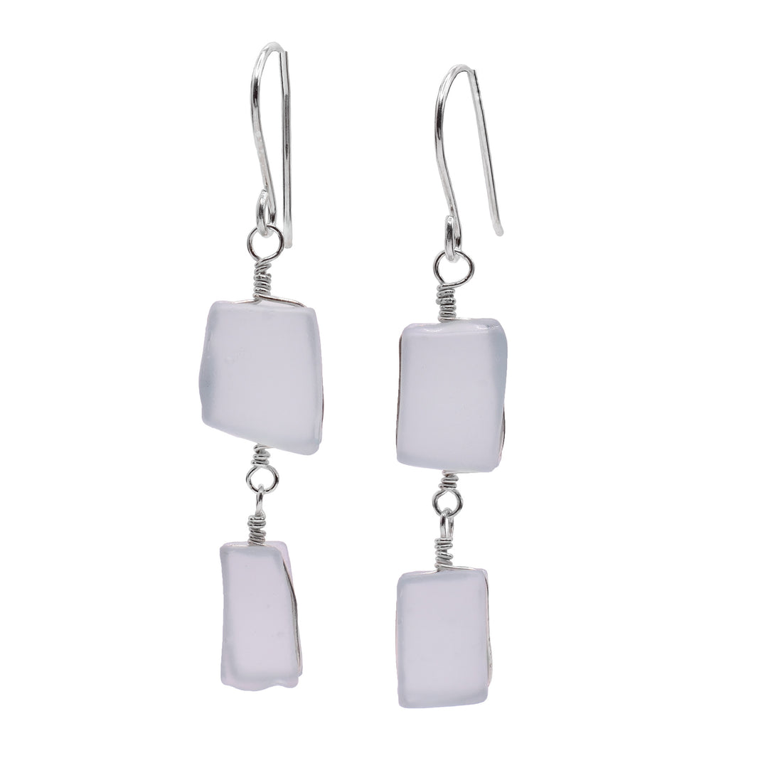 These sea glass dangle earrings have two, square shaped glass pieces hangings down from sterling silver hooks. The pieces of glass are hanging from each other so one is above the other.