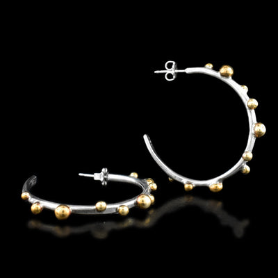 These hoop earrings are circular in shape with round brass accents throughout varying in size. Each earring is stamped with .925 on the back.